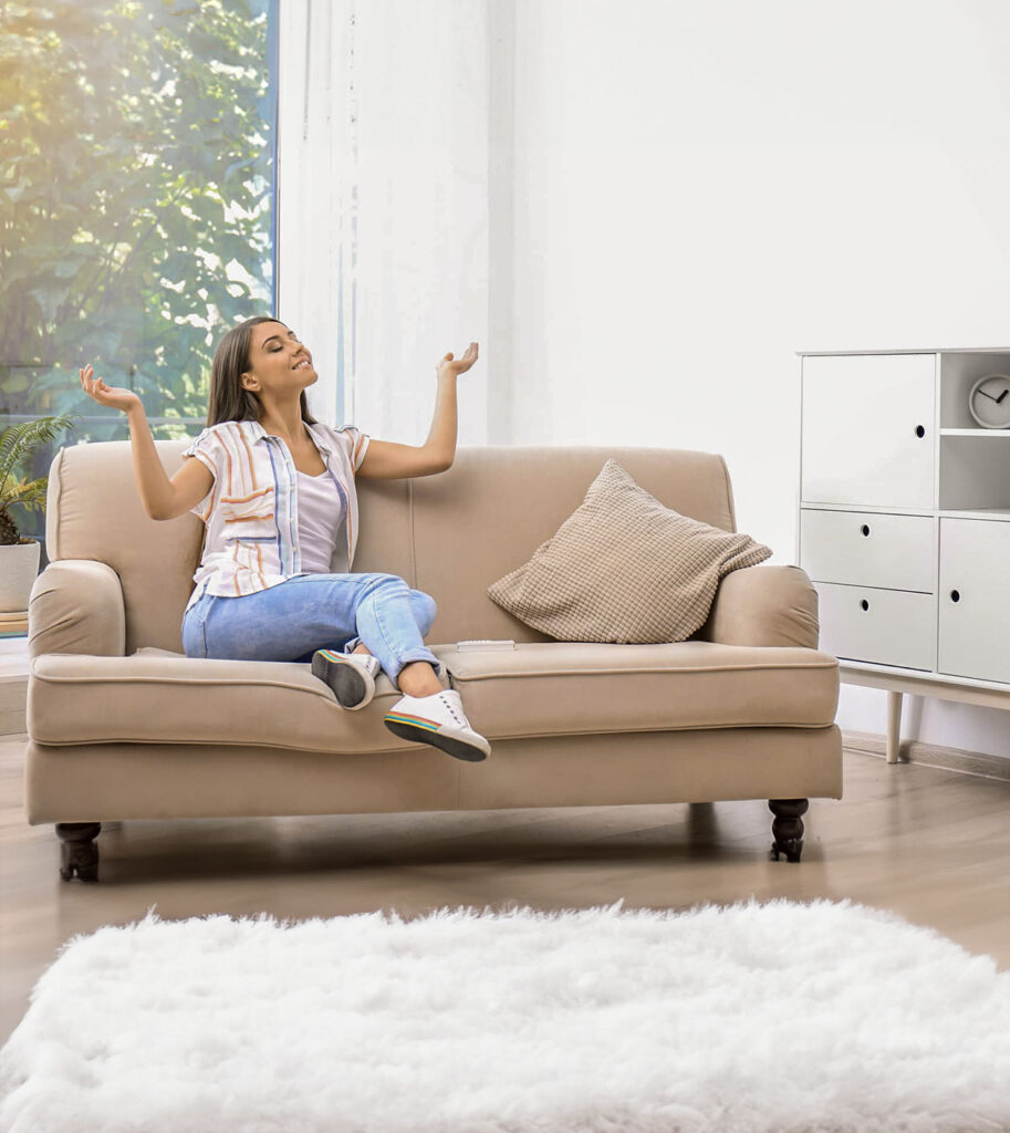 Person entspannt auf einem Sofa und genießt frische Luft aus einem gut belüfteten Raum.